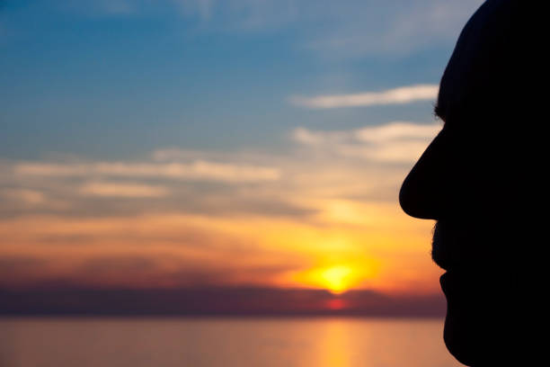 istock Silhouetted man's profile with sunset at sea 1278292112