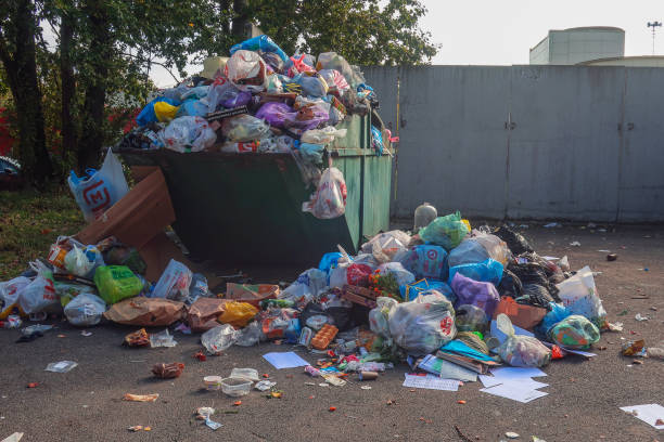 overflowing dumpster with rubbish lying around stock photo