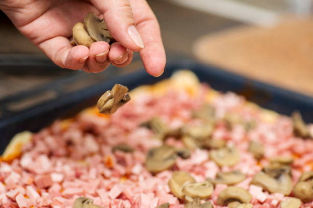 homemade pizza. chef putting mushrooms on pizza in pizza restaurant. pizza making process - pizza sauces chef making imagens e fotografias de stock