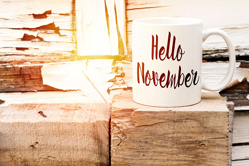 Una taza de café con el texto Hello November sobre el cubo de madera photo