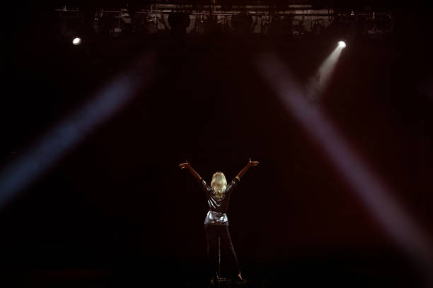 istock A young woman singer on stage during a concert view from the back. 1278304241