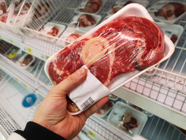 main d’acheteur avec paquet de viande de boeuf à l’épicerie. fermez-vous vers le haut de la viande enveloppée d’homme retenant dans l’épicerie - butcher butchers shop meat store photos et images de collection