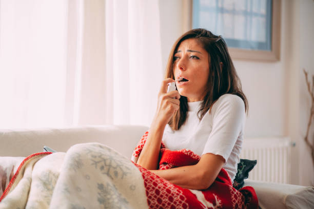 istock Sick Woman Lying on the Sofa Spraying a Medication into Her Throat 1278307292
