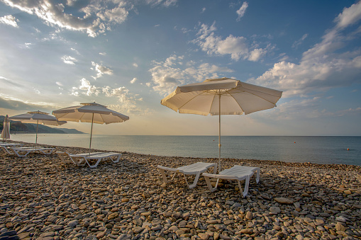 Idyllic morning on the beach: sun loungers and sun umbrellas - the territory of Big Sochi. pebble beach on the beach