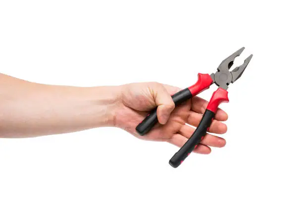 Photo of Pliers in a hand on a white background. Hand is holding universal pliers on white background