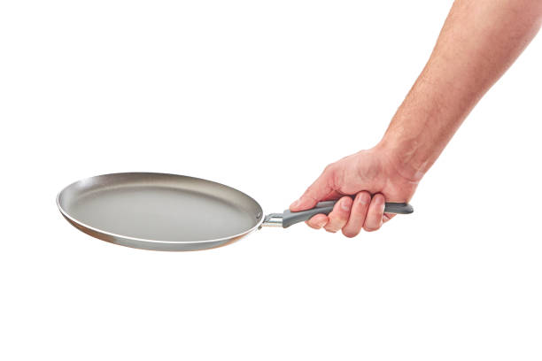 istock Hand holding a black frying pan isolated on white background 1278313606