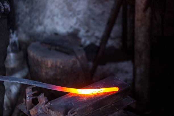 istock In a blacksmith's workshop. Blacksmith in one hand hold a workpiece of hot metal on a anvil. An example of the hard work of ancient crafts. 1278315343
