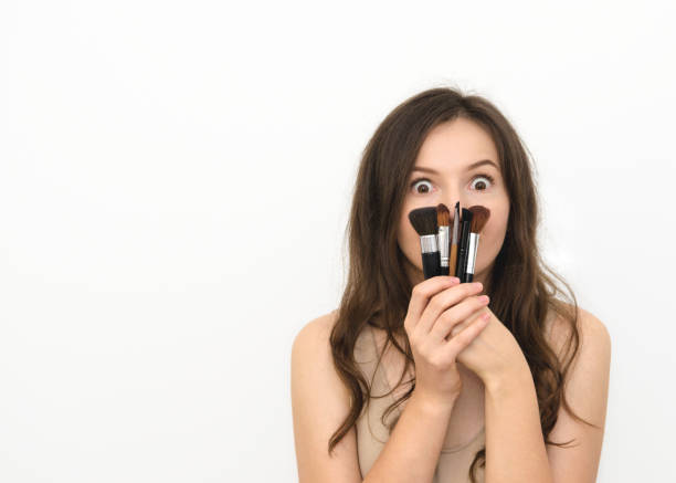 istock a beautiful young woman with make up brushes on a white background 1278317380