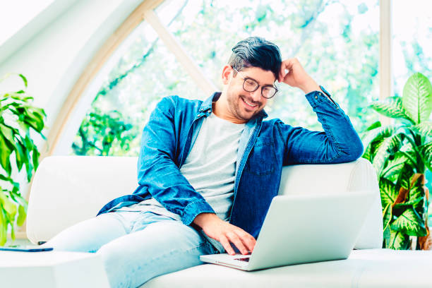 istock Casual and handsome man using his notebook while relaxing on the sofa at home 1278320169