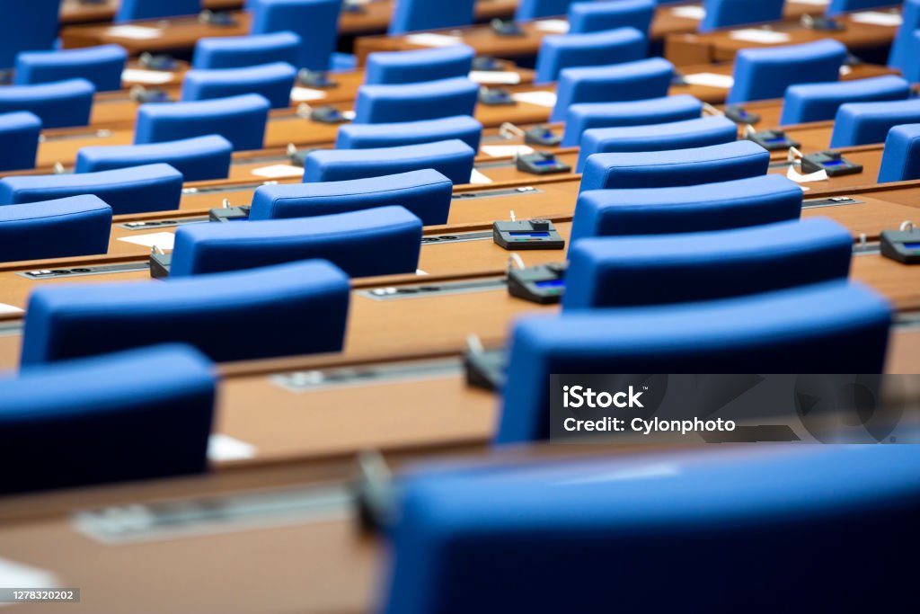 Inside of an empty parliament Inside of an empty parliament hall. Blue chairs in line with voting machines for every seat on the desks. Meeting Stock Photo