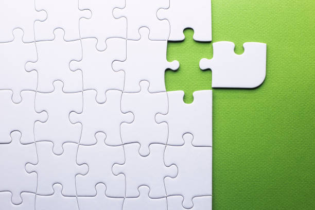 white puzzle with piece that does not fit on a green background a white puzzle with piece that does not fit on a green background oops stock pictures, royalty-free photos & images