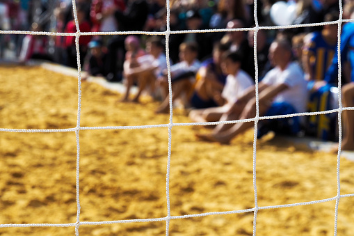 Beach volleyball, spectators through the sports net  for the game of volleyball. Outdoor sports games in summer