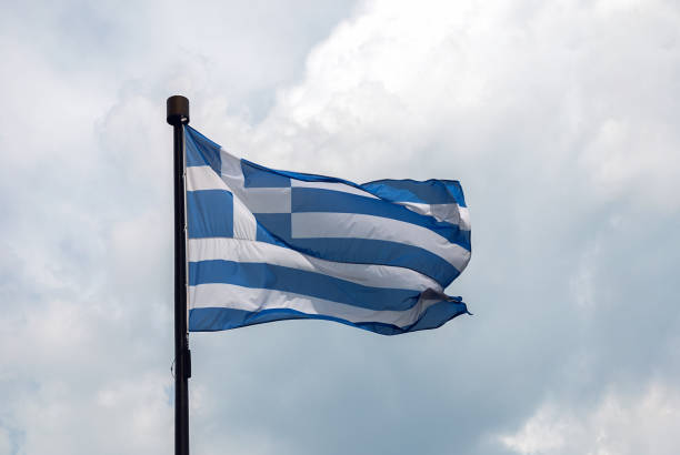 istock Flag of Greece on flagpole on clouds background 1278326755