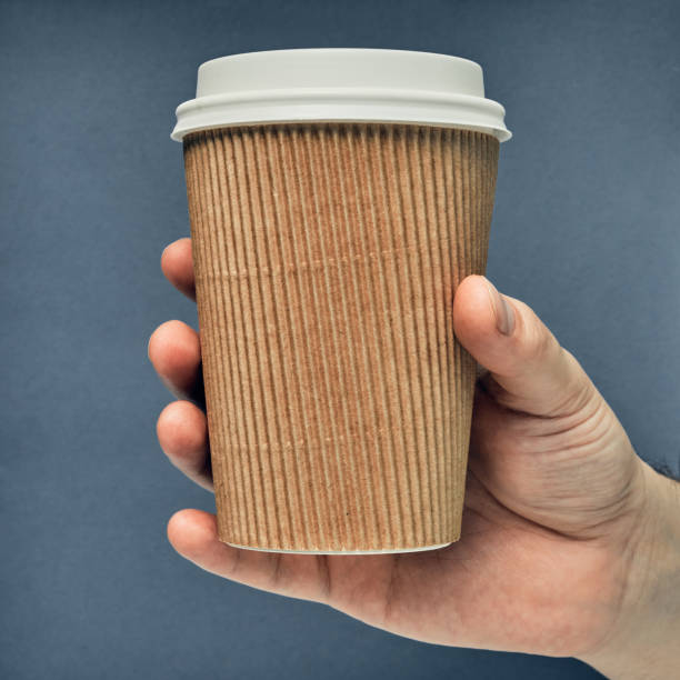 istock Paper cup in hand on a colored background. Eco-friendly materials in a coffee shop, biodegradable disposable tableware. Close up 1278329887
