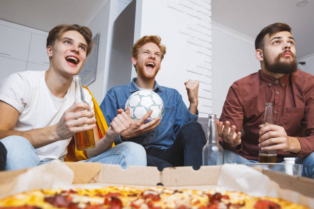 mężczyźni oglądają sport w telewizji razem w domu aktywny doping - sitting 20s adult american football zdjęcia i obrazy z banku zdjęć
