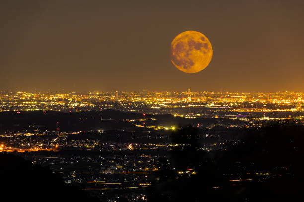A full orange harvest moon rise over a city The view from Yunoyama onsen village in Komono. A big orange harvest moon rise over Yokkaichi city in Mie prefecture, Japan. red full moon stock pictures, royalty-free photos & images