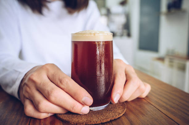 Someone holding a glass of Nitro cold brew coffee.