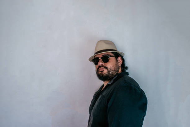 istock handsome latin man with beard wearing glasses and hat while looking at camera 1278343712