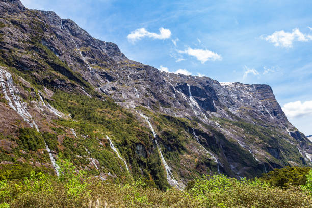 pequeñas cascadas y arroyos desde acantilados en el camino a fiordland. south island, nueva zelanda - alp descent fotografías e imágenes de stock