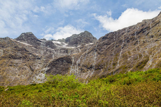 una pared de pequeñas cascadas desde acantilados en el camino a fiordland. nueva zelanda - alp descent fotografías e imágenes de stock