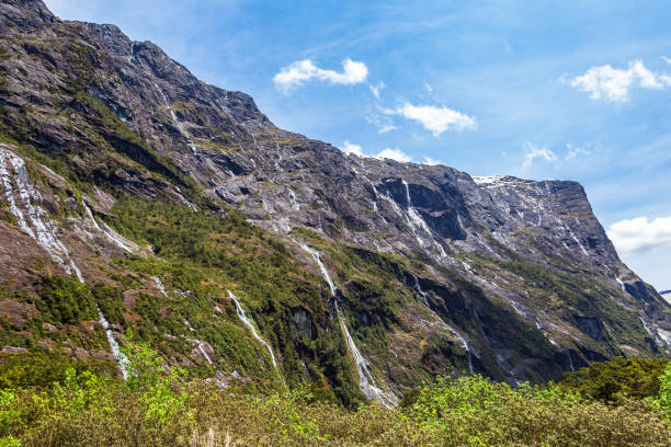 pequeñas cascadas y arroyos desde acantilados en el camino a fiordland. nueva zelanda - alp descent fotografías e imágenes de stock