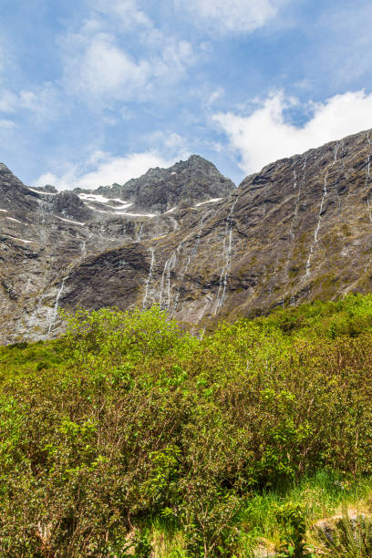 panorama con pequeñas cascadas en el camino a fiordland. south island, nueva zelanda - alp descent fotografías e imágenes de stock