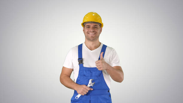 trabajador con llave mostrando el pulgar hacia arriba y sonriendo a la cámara en gra - manual worker thumbs up hand sign adult fotografías e imágenes de stock
