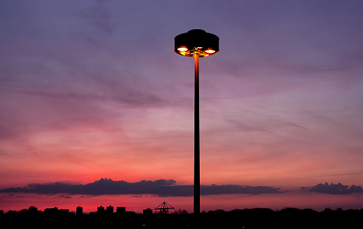 A fading, orange sunset behind a part of Toronto’s skyline and a street lamp.