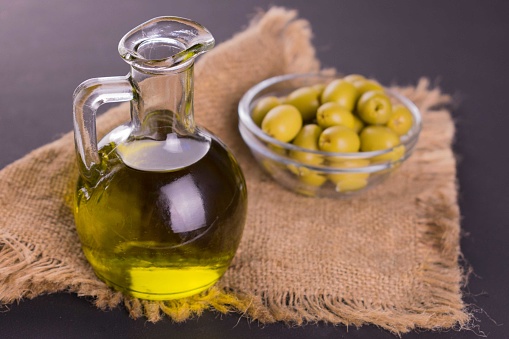 Decanter with olive oil and olives in  a bowl. Close-up.