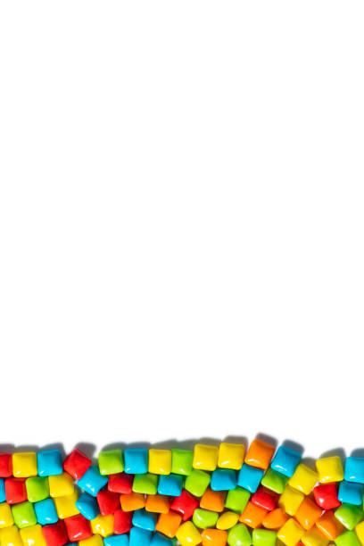 istock Candies. Color candy on the bottom on white background top view frame copy space. Chewing gum, and dragees are scattered. Space for text. Vertical photo 1278360164