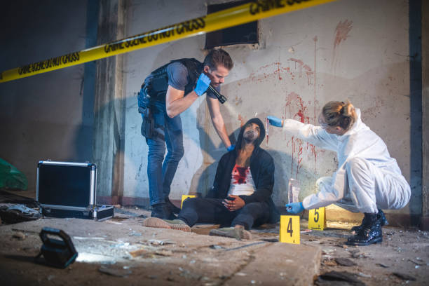 istock Young Policeman Shining Flashlight on Bloody Knife Evidence 1278360822