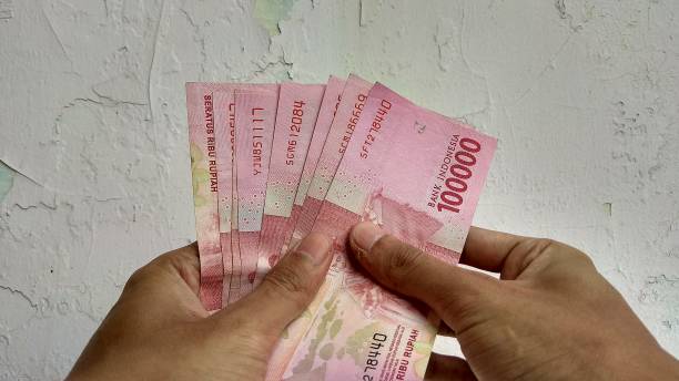 istock a man's hand was holding a 100,000 rupiah bill 1278361960