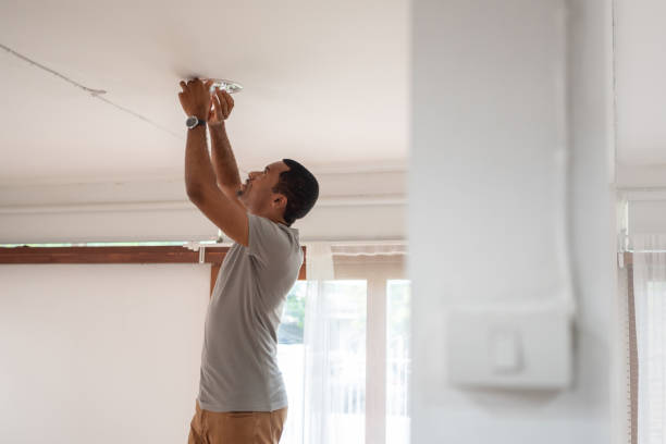 african american man changing light bulb during covid-19 quarantine at home - household equipment light bulb compact fluorescent lightbulb lighting equipment imagens e fotografias de stock