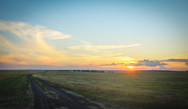 istock Summer sunset rural landscape with country road and dramatic sky over the fields. 1278366408