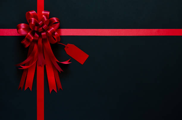 istock Red ribbon with bow and price tag on black background. 1278368358