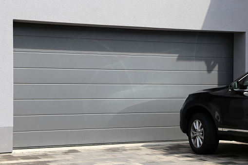 Modern garage door with black car parked in front