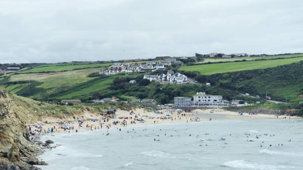 busy english beach in the summer with lots of families together. lifeguards look over them in the water - lifeguard association imagens e fotografias de stock