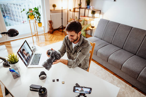 vlogger testet neue kamera und objektiv - mann nimmt sich selbst im wohnzimmer auf - video voip fotos stock-fotos und bilder