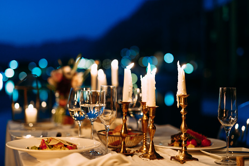 Candles in candlesticks with glasses and treats on the table in the evening with shallow depth of field. High quality photo