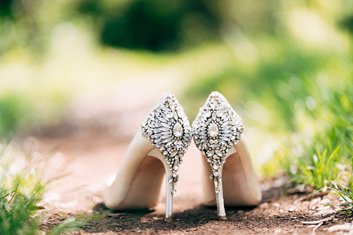 Bride's shoes with a backdrop decorated with stones on the ground in nature with shallow depth of field. High quality photo