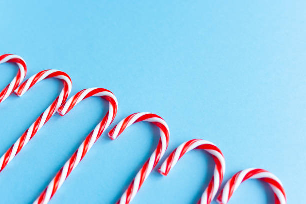 istock Christmas composition. Christmas candy canes in row flat lay, top view on pastel pink background.Holiday festive celebration greeting card with copy space fo text. Christmas background with candy canes and fir branch, banner, postcard 1278385719