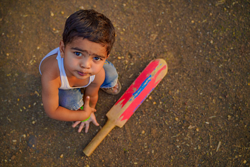 Cute indian little child playing cricket at home