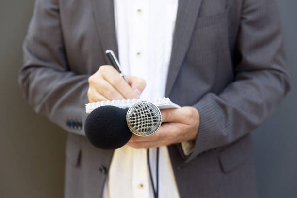 istock Journalist at news conference or media event, writing notes, holding microphone 1278391833