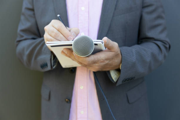 istock Journalist at news conference or media event, writing notes, holding microphone 1278393199