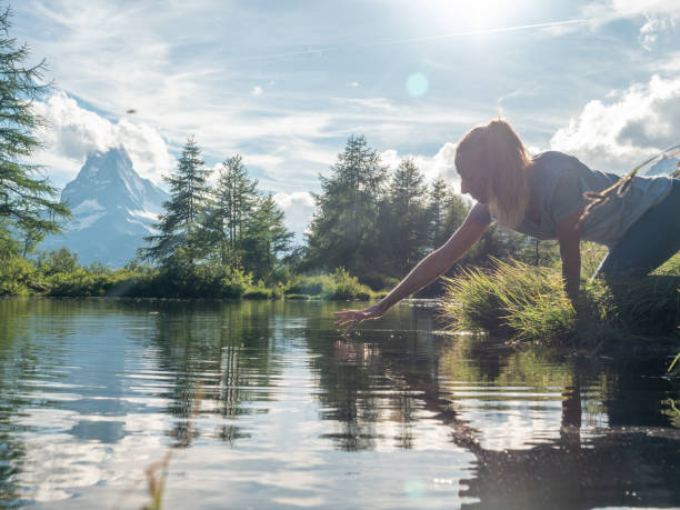 istock Woman scooping water from alpine lake 1278393339