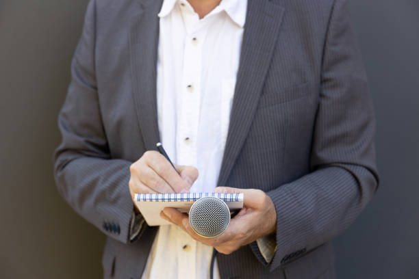 istock Journalist at news conference or media event, writing notes, holding microphone 1278395637