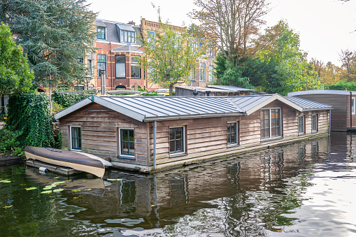 Leiden, Netherlands - September 2020: Scenic view of wooden houseboats floating in a canal in the city of Leiden, Holland.