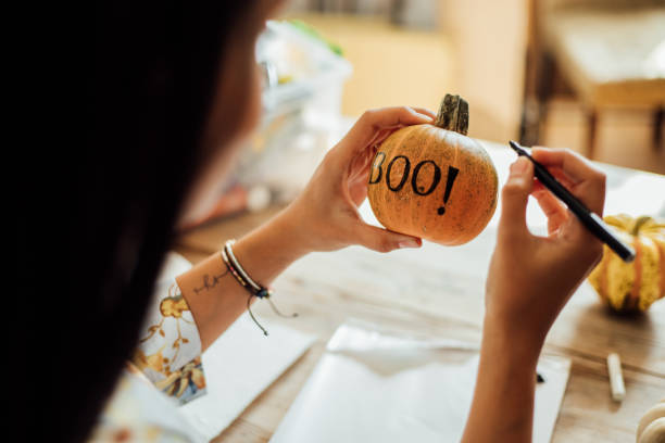 istock Woman drawing spooky face on a pumpkin for Halloween 1278397786