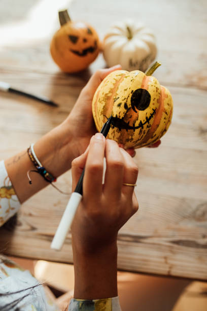 istock Woman drawing spooky face on a pumpkin for Halloween 1278398542