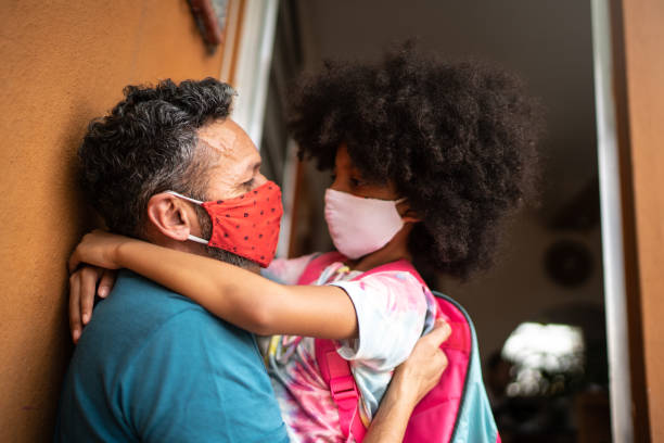 istock Girl using face mask going to /arriving from school and embracing father 1278398577
